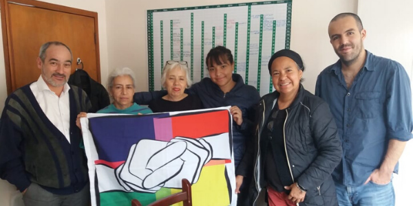 Staff members of Corporacion Araza gather in a line holding the organization's flag