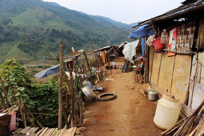 shacks for refugees on right, dirt path down the middle and cliff down to hills on left