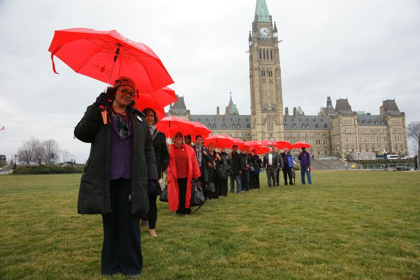 Medicare advocates on Parliament Hill in Ottawa with red umbrellas