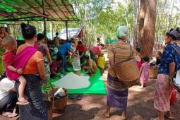 Photo showing many people, including children and babies, waiting for food distribution.