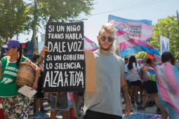 A protester raises a placard that says in Spanish, “If a trans child speaks, give them a voice. If a government silences them, raise yours.”