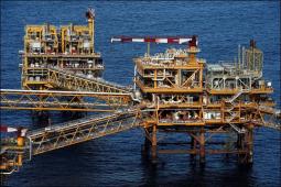 Photo of an offshore oil rig. There are two main looking structures and open, metal bridges radiating out from the one on the right.